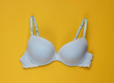 Sarı arka planda şık bir sütyen. Üst Manzara. Güzellik ve moda minimalist natüralistik hayat