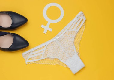 Kadınların seksi dantelli külotları, yüksek topuklu ayakkabılar ve sarı arka planda cinsiyet sembolü. Feminizm kavramı. Üst görünüm