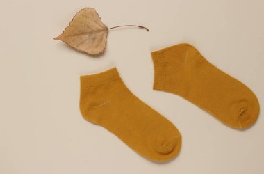 Sonbahar geldi. Bej arka planda kurumuş yapraklı turuncu çoraplar. Üst görünüm