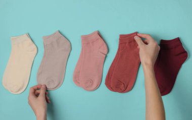 Kadın eli mavi arka planda renkli bir çorabı katlıyor. Üst görünüm