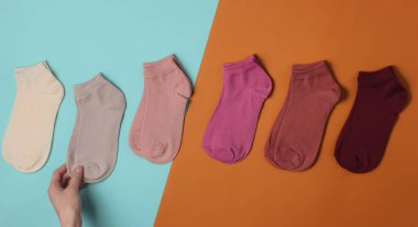 Kadın eli mavi kahverengi arka planda bir çift sıradan renkli çorap seçer. Üst görünüm