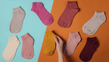 Kadın eli mavi kahverengi arka planda bir çift sıradan renkli çorap seçer. Üst görünüm