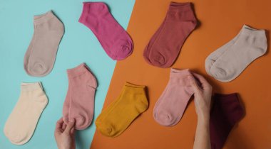 Kadın eli mavi kahverengi arka planda renkli bir çorabı katlıyor. Üst görünüm