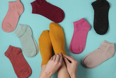 Kadın, diğer renkli çoraplar arasında mavi arka planda çorap giyer. Stüdyo çekimi. Üst görünüm