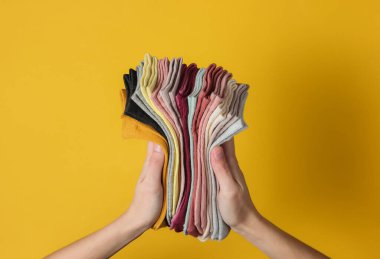 Stüdyonun sarı arka planında kadın çorapları tutuyor. Üst görünüm