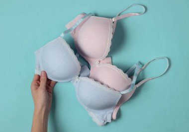 Mavi stüdyo arka planında kadın eli sutyenleri tutuyor. Üst görünüm