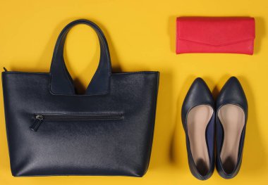 Çanta, çanta, sarı arka planda yüksek topuklu ayakkabılar. Kadının günlük kıyafetinin genel görünüşü. Moda kadın aksesuarları. Düz yatış, üst görünüm.