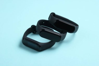 Mavi arka planda üç akıllı bilezik. Spor ve günlük aktiviteler için modern aletler