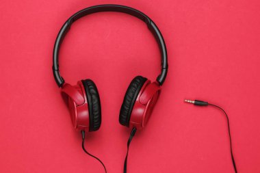 Kırmızı arka planda kırmızı kulaklıklar. Müzik aşığı kavramı.
