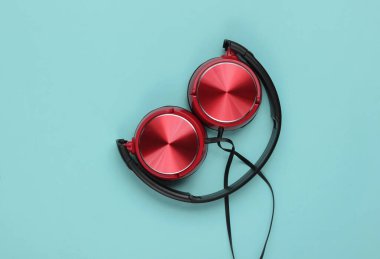 Şık, mavi arka planda kırmızı kulaklık. Müzik aşığı konsepti. Üst görünüm