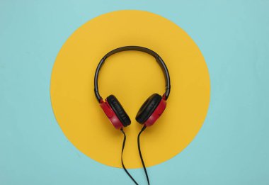 Mavi pastel arka planda sarı daireli modern kulaklıklar. Müzik aşığı kavramı.