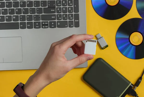 Vrouwelijke Hand Houdt Geheugenkaart Een Achtergrond Van Gadgets Bovenaanzicht — Stockfoto