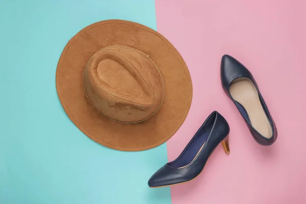 Felt hat, high heel shoes on pink blue pastel background. Minimalistic fashion concept. Top view