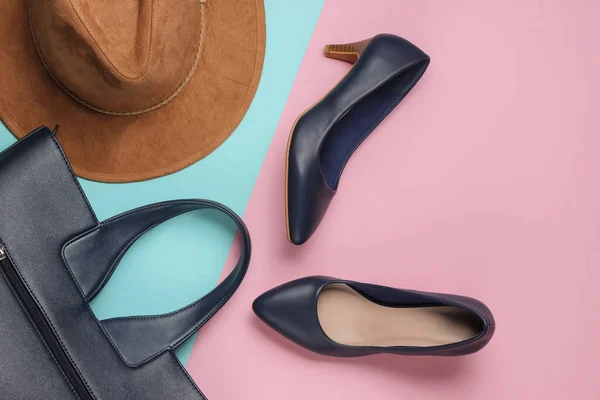 Felt hat, high heel shoes, leather bag on pink blue pastel background. Minimalistic fashion concept. Top view