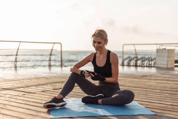 Vrolijke Fitness Vrouw Zit Mat Maakt Gebruik Van Een Smartphone — Stockfoto