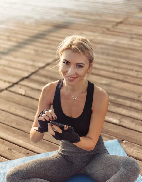 Vrolijke Fitness Vrouw Zit Mat Maakt Gebruik Van Een Smartphone — Stockfoto