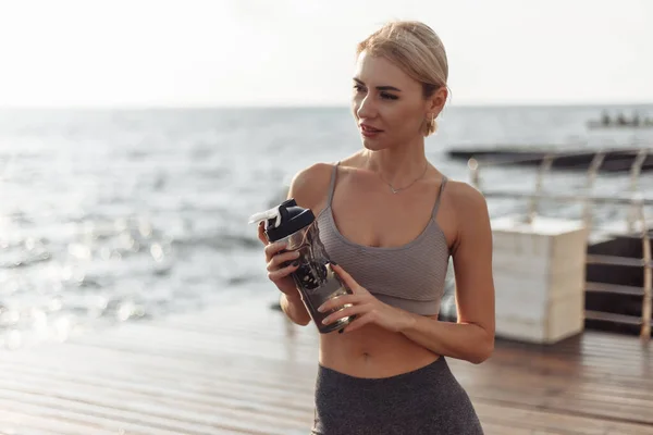 Młoda Fitness Kobieta Trzyma Butelkę Wody Plaży Wschodzie Słońca — Zdjęcie stockowe