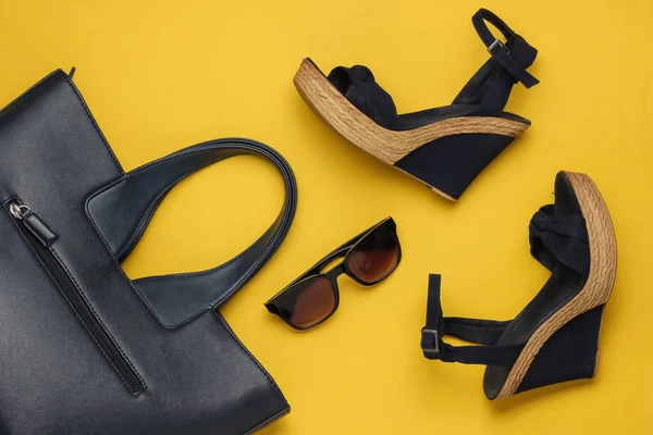 Platformu, çantası, sarı arka planda güneş gözlüğü olan kadın sandaletleri. Kadın yaz ayakkabıları ve aksesuarları. Üst görünüm.
