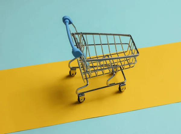 简约购物的概念 蓝黄色背景的购物车 — 图库照片
