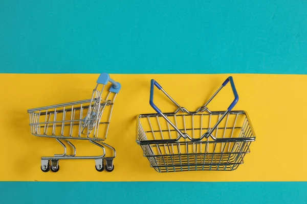 Minimalistisches Einkaufskonzept Warenkorb Und Einkaufswagen Auf Blau Gelbem Hintergrund Ansicht — Stockfoto