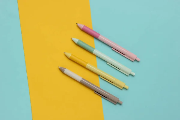 A lot of colored pens close-up on yellow blue background.