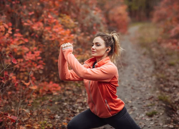 Młoda Atrakcyjna Sportowiec Odzieży Sportowej Robi Ćwiczenia Rozciągające Jesiennym Lesie — Zdjęcie stockowe