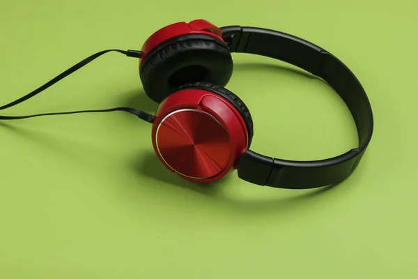 緑の背景にスタイリッシュな有線赤のヘッドフォン 音楽愛好家のコンセプト — ストック写真