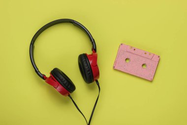 Kablolu kulaklıklar ve yeşil arka planda ses kaseti. Retro tarzı DJ. Üst görünüm, minimalist müzik konsepti.