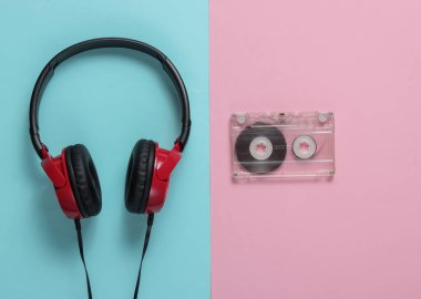 Üzerinde mavi pastel arka planda ses kaseti olan kablolu kulaklıklar. Retro tarzı DJ. Üst görünüm, minimalist müzik konsepti.
