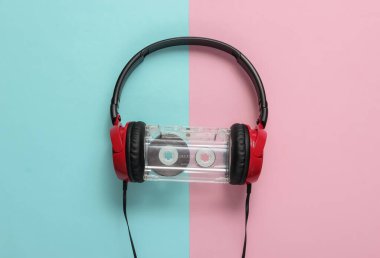 Üzerinde mavi pastel arka planda ses kaseti olan kablolu kulaklıklar. Retro tarzı DJ. Üst görünüm, minimalist müzik konsepti.