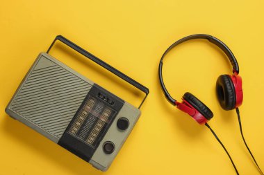 FM radyo alıcısı, sarı arka planda eski tarz kulaklıklar. Müzik aşığı konsepti. Üst Manzara. 70 'ler