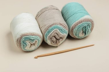 Bej bir arka planda yün iplik ve örgü kancası.