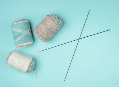 Mavi arka planda örgü iğneleriyle yünlü yün iplikler. Ev Kadınları Hobileri