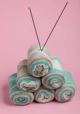 Pembe arka planda örgü iğneleriyle yün ipliklerin derileri. Ev Kadınları Hobileri.