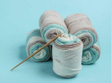 Mavi arka planda yün iplik ve örgü kancası.