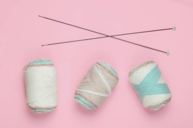 Pembe arka planda örgü iğneleriyle yün ipliklerin derileri. Ev Kadınları Hobileri. Üst görünüm