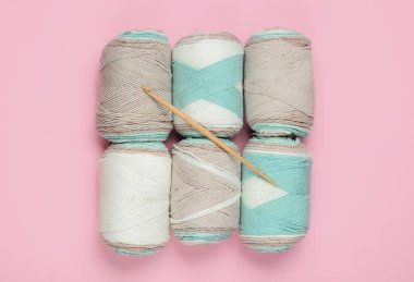 Pembe pastel arka planda yün iplik ve örgü kancası. Üst görünüm
