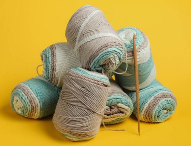 Pastel renklerin yün iplikleri ve sarı arkaplanda tığ işi kanca. Ev Kadınları Hobileri