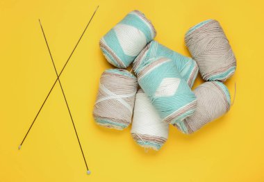 Pastel renkli yün iplikler, sarı stüdyo arka planında örgü iğneleri. Üst Manzara. Stüdyo çekimi. Hobi ev yapımı