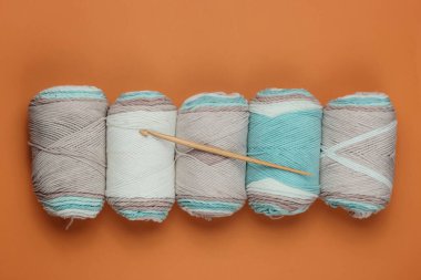 Pastel renklerin yün derileri, kahverengi arka planda ahşap örgü kancası. Üst görünüm