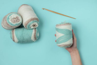 Mavi arka planda yün iplik yumağı tutan kadınların elleri. Ev Kadınları Hobileri. Üst görünüm