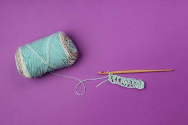 İplikli yün iplikler ve mor arka planda ahşap bir kanca. Üst Manzara. Hobiler