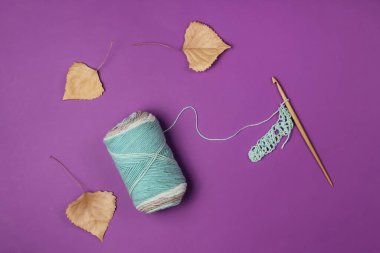 İplikli yün iplikler ve mor arka planda ahşap bir kanca. Üst Manzara. Sonbahar Hobileri