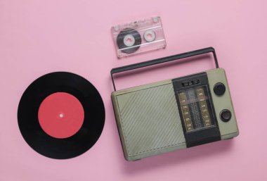 Retro radyo alıcısı, eski moda vinil kayıt, pembe pastel arka planda ses kaseti. Medya 70 'ler. Üst görünüm