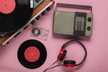 Retro radyo alıcısı, eski moda vinil çalar, kulaklıklar, pembe pastel arka planda ses kaseti. Medya 70 'ler. Üst görünüm