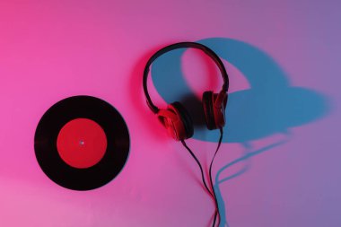 Kablolu kulaklıklar ve neon mavi-kırmızı gradyan ışıklı vinil plaklar. Retro dalga, 80 'lerin popüler kültürü. Üst görünüm