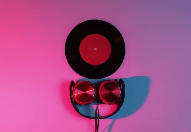 Kablolu kulaklıklar ve neon mavi-kırmızı gradyan ışıklı vinil plaklar. Retro dalga, 80 'lerin popüler kültürü. Üst görünüm