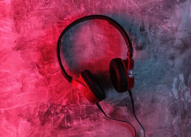 Beton arka planda kablolu kulaklıklar. Neon mavi-kırmızı eğimli ışık. Retro dalga, 80 'lerin popüler kültürü. Üst görünüm