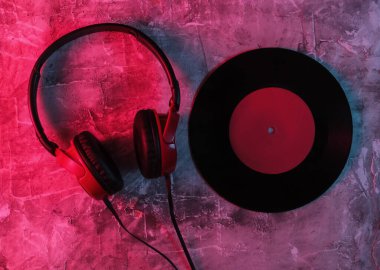 Kablolu kulaklıklar ve beton arka planda plaklar. Neon mavi-kırmızı eğimli ışık. Retro dalga, 80 'lerin popüler kültürü. Üst görünüm