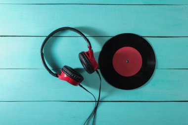 Kablolu kulaklıklar ve mavi ahşap arka planda plaklar. Retro dalga, 80 'lerin popüler kültürü. Üst görünüm